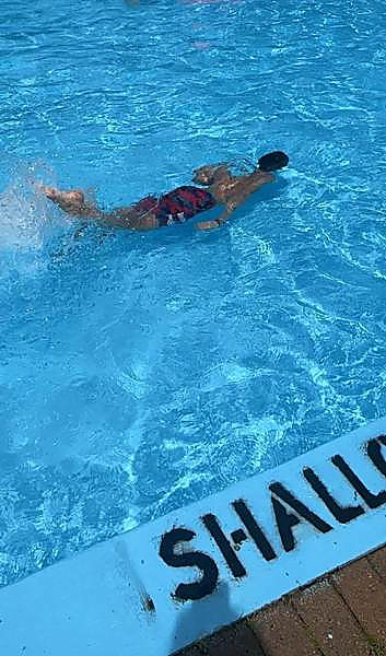 A camper swimming a length in the shallow end of the pool
