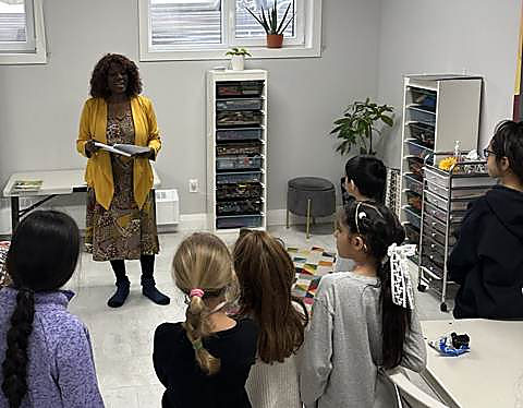 A community visitor reading out words to a group of kids at a spelling bee