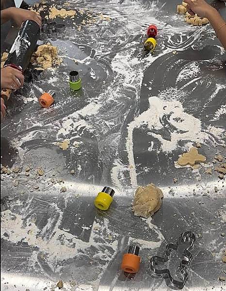 A floury steel table covered in cookie cutters and dough during a baking session at Hexagon