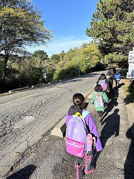 A line of kids walking with backpacks down the road into Sunnybrook Park
