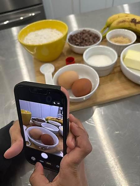 A phone photographing baking ingredients laid out on a board