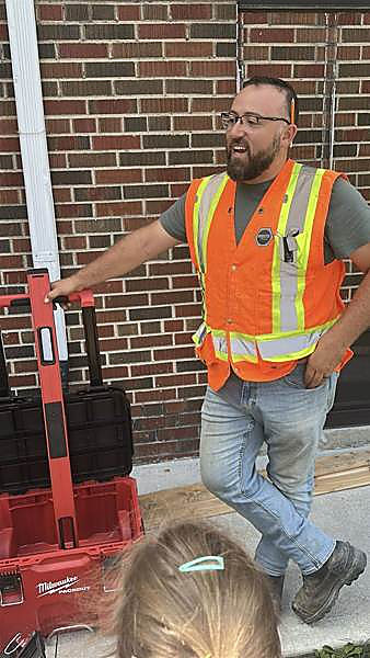 A tradesperson showing kids a level and a site toolbox on a community visit