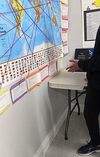 A world map strung with red yarn beside a student project presentation
