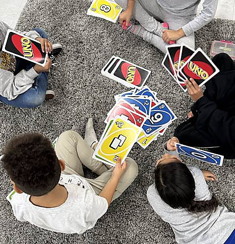 An UNO tournament in progress on the rug, seen from above