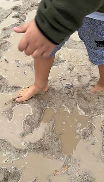 Bare feet in wet sand at the water’s edge on a nature walk