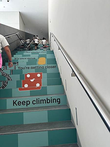 Kids climbing a gallery staircase painted with a game board on a museum trip
