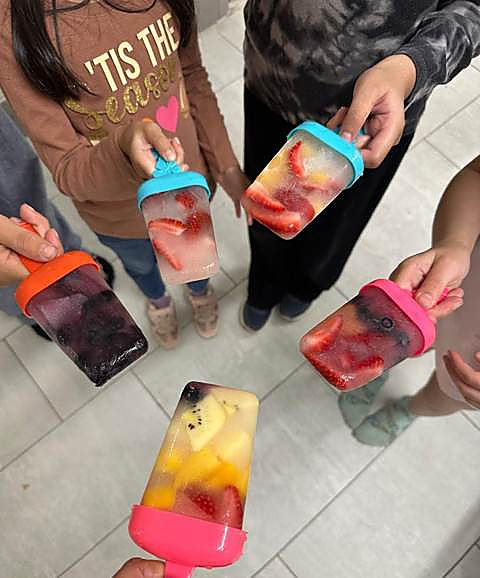 Kids holding up homemade fruit popsicles they froze themselves