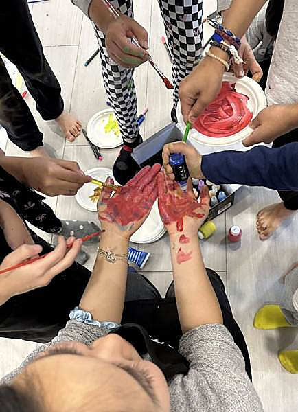 Kids painting each other's palms with poster paint during a group art project