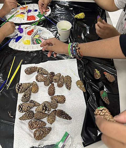 Kids painting pinecones they collected, laid out to dry on paper towel
