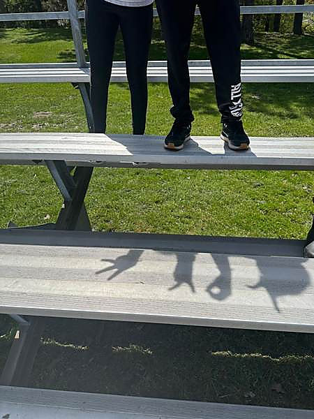 Shadows of kids stretched across the bleachers on a sunny day